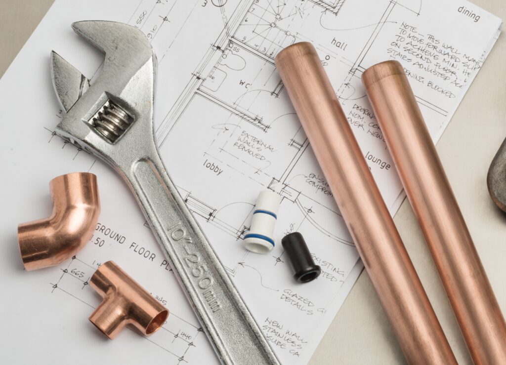 Des outils et matériaux de plomberie sur un plan.